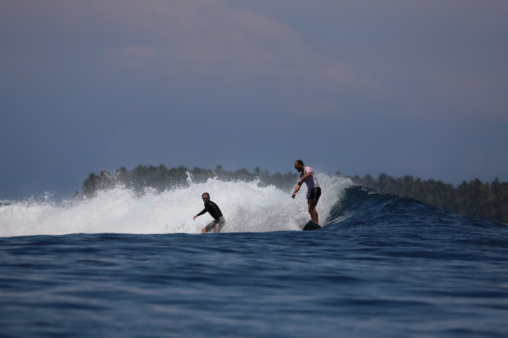Two surfers riding a breaking wave together in tropical water